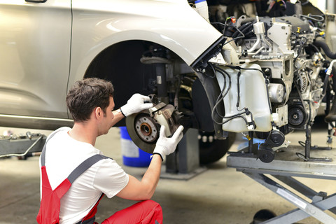 Automechaniker in einer Werkstatt bei der Arbeit am Auto, lizenzfreies Stockfoto