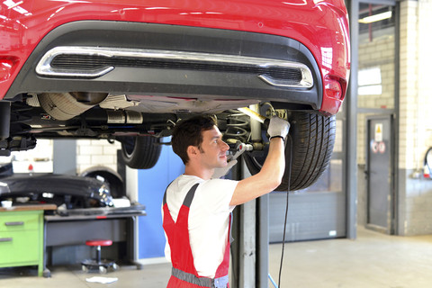 Automechaniker in einer Werkstatt bei der Arbeit am Auto, lizenzfreies Stockfoto