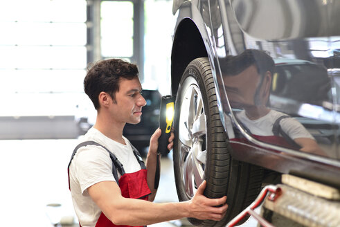 Automechaniker in einer Werkstatt prüft Reifen - LYF000030