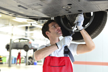 Automechaniker in einer Werkstatt bei der Arbeit am Auto - LYF000033