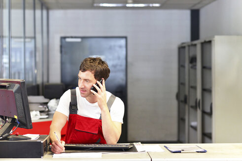 Automechaniker am Telefon im Servicebereich einer Autowerkstatt - LYF000007