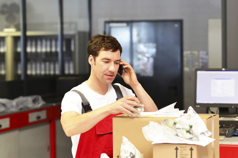 Automechaniker am Telefon im Servicebereich einer Autowerkstatt, lizenzfreies Stockfoto