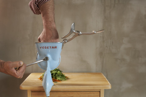 Mann hält seine Hand in den Gemüsehäcksler, Teilansicht, lizenzfreies Stockfoto