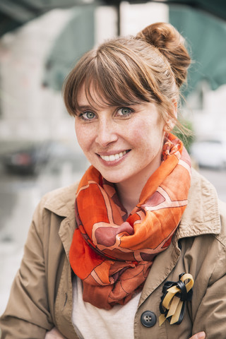 Porträt einer lächelnden Frau mit Sommersprossen und orangefarbenem Halstuch, lizenzfreies Stockfoto