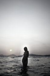 Naked young woman standing in the sea by twilight - AJF000042