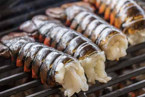 Lobster tails cooking over charcoal on barbecue grill stock photo