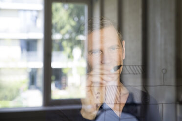 Portrait of business man drawing sketch on glass pane - FKF000489