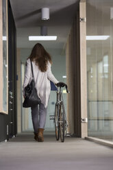 Geschäftsfrau verlässt Büro mit Rennrad - FKF000499