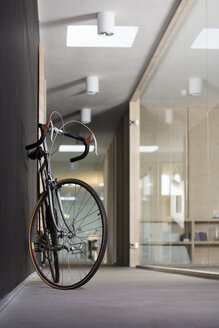 Rennrad im Korridor eines modernen Büros stehend - FKF000500