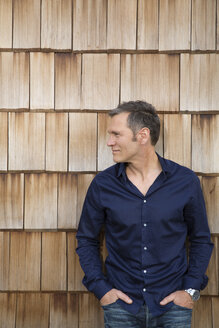Portrait of creative business man in front of wood shingle panelling - FKF000510