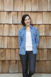 Portrait of young creative business woman in front of wood shingle panelling - FKF000513