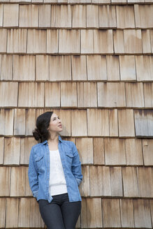 Portrait of young creative business woman in front of wood shingle panelling - FKF000515