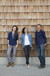Gruppenbild von drei kreativen Geschäftsleuten vor einer Holzschindelverkleidung - FKF000518
