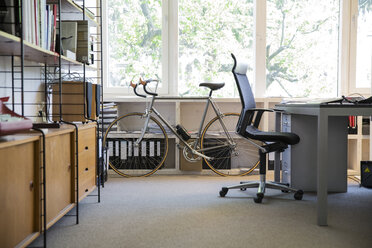 Rennrad stehend am Arbeitsplatz eines modernen Büros - FKF000522