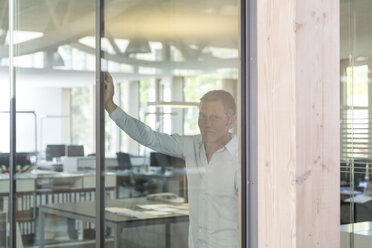 Portrait of smiling creative business man behind glass panel - FKF000531