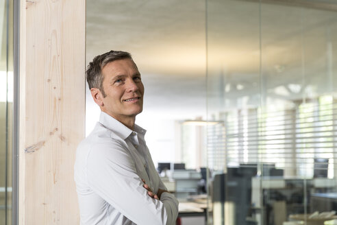 Portrait of smiling creative business man in front of office - FKF000534