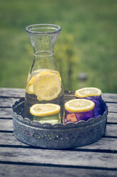 Tablett, Karaffe mit Limonade und Zitronenscheiben auf farbigen Gläsern - SARF000653
