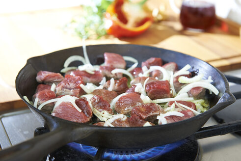 Preparing beef goulash in frying pan on gas stove - SRSF000495