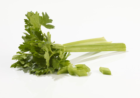 Zwei Stangen und Teile von Sellerie vor weißem Hintergrund, lizenzfreies Stockfoto