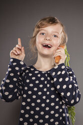 Porträt eines kleinen Mädchens, das eine Karotte als Telefon benutzt - OJF000020