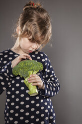 Portrait of little girl examining a broccoli - OJF000025