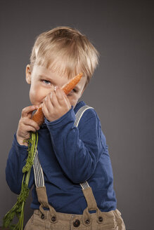 Porträt eines kleinen Jungen, der mit einer Karotte spielt - OJF000037