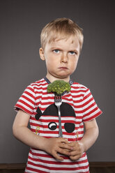 Portrait of angry looking little boy holding fork with broccoli - OJF000038