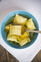 Bowl of stock with Swabian dumplings and spoon on white cloth, elevated view - LVF001333