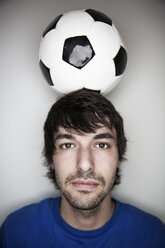 Young man balancing soccer ball on head - JATF000721