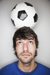 Junger Mann balanciert Fußball auf dem Kopf - JATF000722