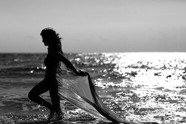 Silhouette einer jungen Frau bei einem Spaziergang am Meer - AJF000047