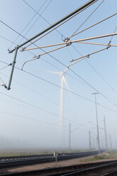 Deutschland, Hamburg, Windkraftanlage neben Bahngleisen im Frühnebel - MSF003980