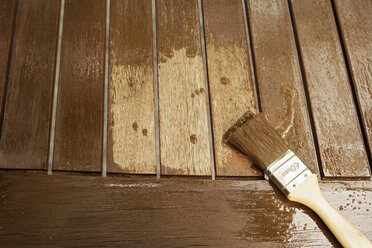 Applying glaze with brush on wooden bench, partial view - ONF000555