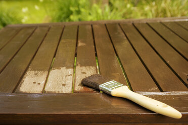 Applying glaze with brush on wooden bench, partial view - ONF000556