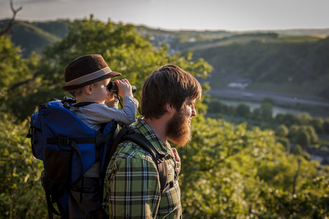 Deutschland, Rheinland-Pfalz, Moselsteig, Vater und sein kleiner Sohn betrachten die Aussicht mit einem Fernglas, lizenzfreies Stockfoto