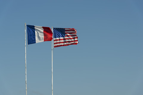 Frankreich, Normandie, Manche, Sainte Marie du Mont, Utah Beach, französische und US-amerikanische Flagge wehen vor blauem Himmel, lizenzfreies Stockfoto