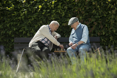 Zwei alte Freunde sitzen auf einer Parkbank und spielen Schach - UUF000736