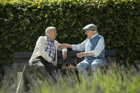 Zwei alte Freunde sitzen auf einer Parkbank und spielen Schach - UUF000737