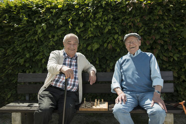 Two old friends sitting on park bench with chess - UUF000739