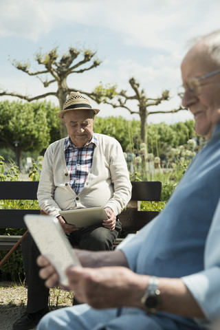 Deutschland, Worms, Zwei alte Männer benutzen Tablet-Computer im Park, lizenzfreies Stockfoto