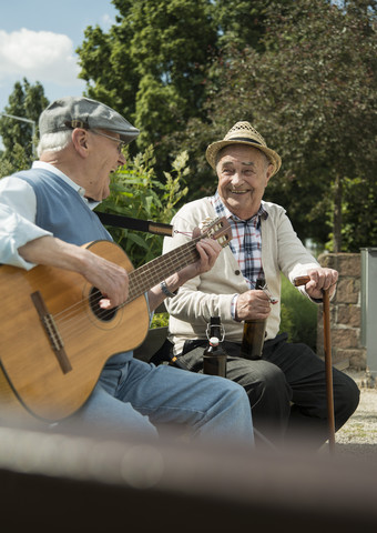Zwei alte Männer mit Gitarre im Park, lizenzfreies Stockfoto
