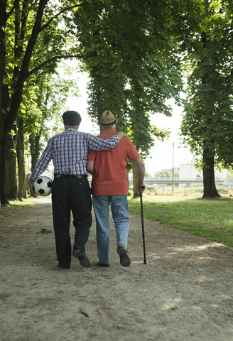 Zwei alte Freunde beim Spaziergang im Park mit Fußball, Rückansicht, lizenzfreies Stockfoto