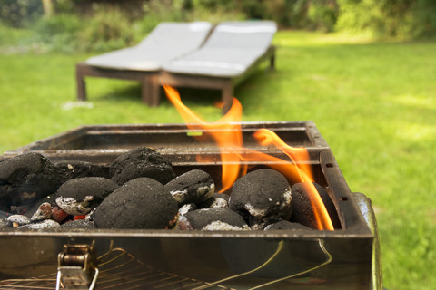 Burning coal briquets on grill in garden stock photo