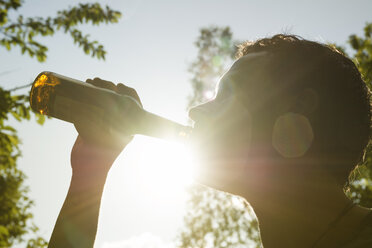 Mann trinkt Bier aus einer Flasche im Sonnenlicht - ONF000596