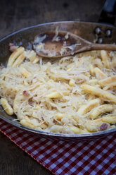 Frying pan of finger-shaped potato dumplings with sauerkraut and bacon on cloth, partial view - LVF001370