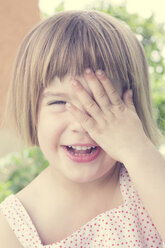 Portrait of laughing little girl covering one eye with her hand - LVF001354