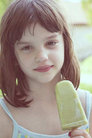 Porträt eines träumenden Mädchens mit grünem Eislutscher, lizenzfreies Stockfoto