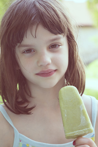 Portrait of daydreaming girl with green ice lolly stock photo