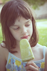 Portrait of daydreaming girl with green ice lolly - LVF001358