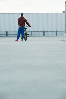 Boy with BMX bike and headphones on parking level - UUF000813